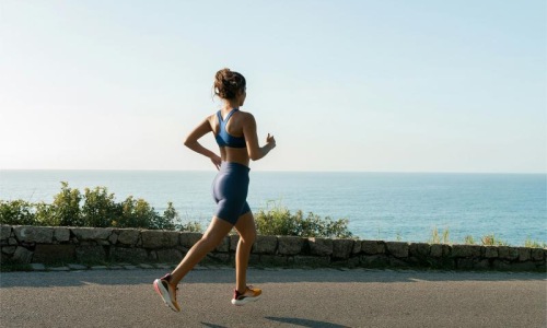 a woman running on a road by the water